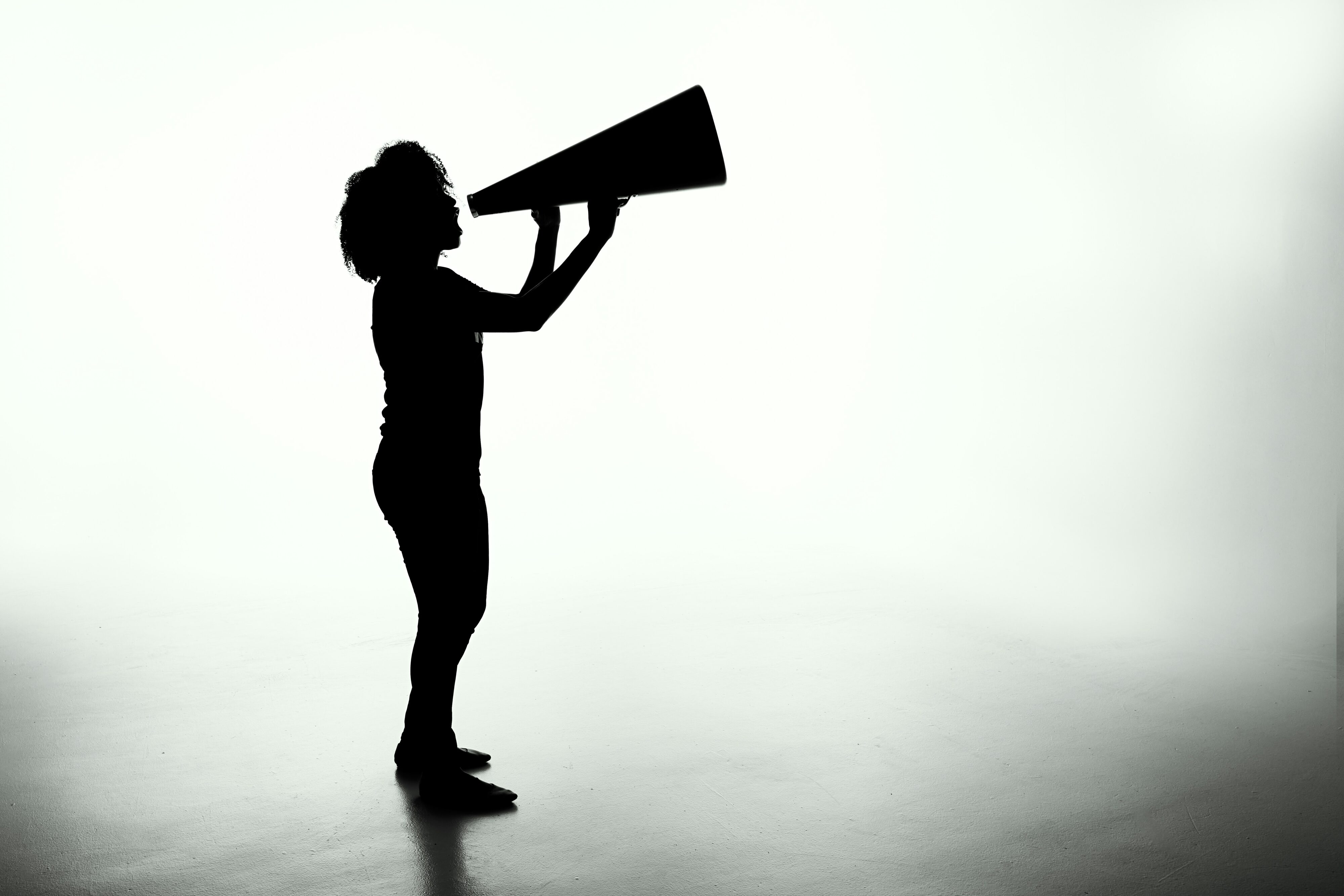Silhouette of person shouting into a megaphone